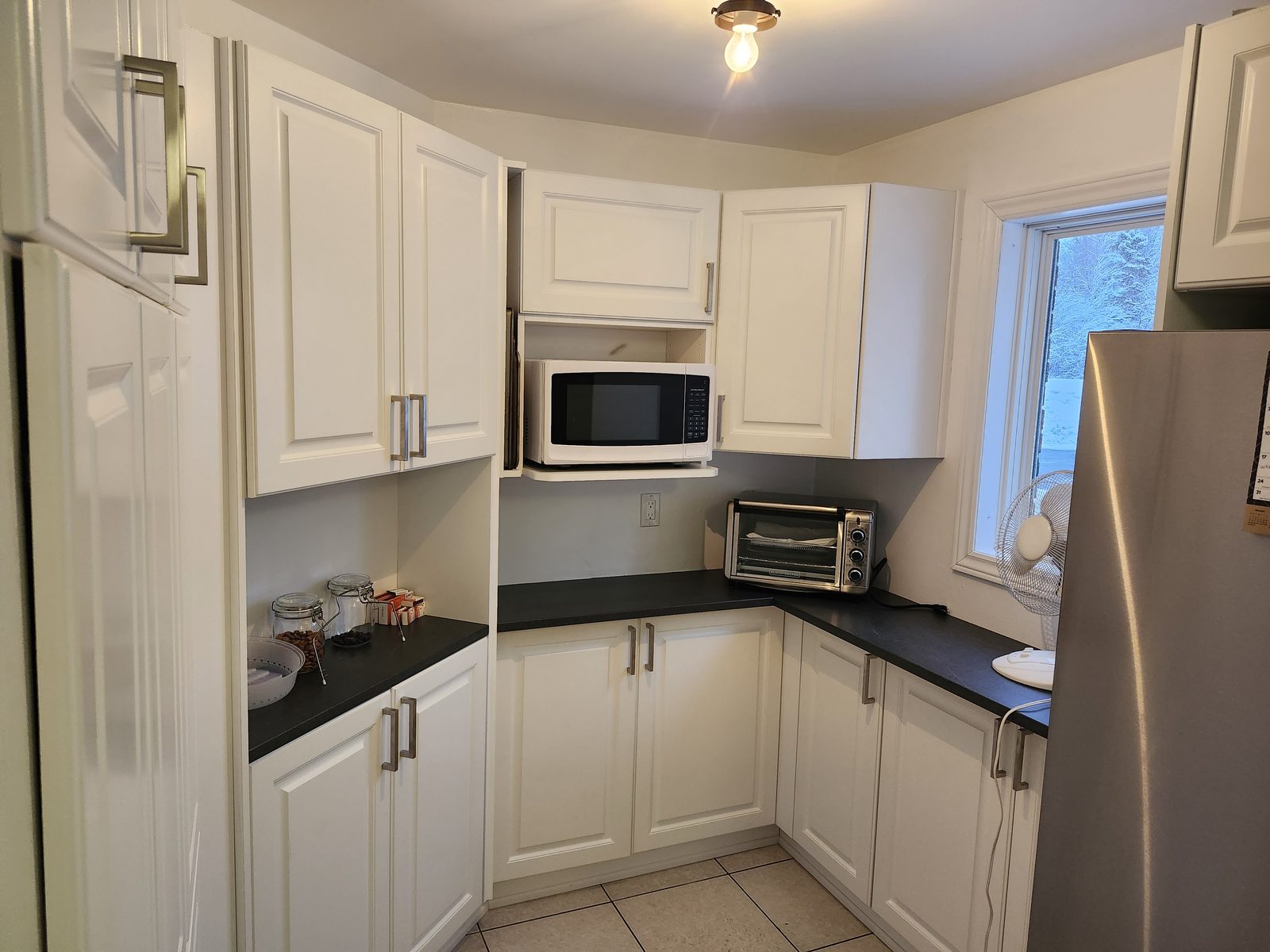 A refaced white kitchen in Ottawa with raised-panel doors, new hardware and a dark countertop