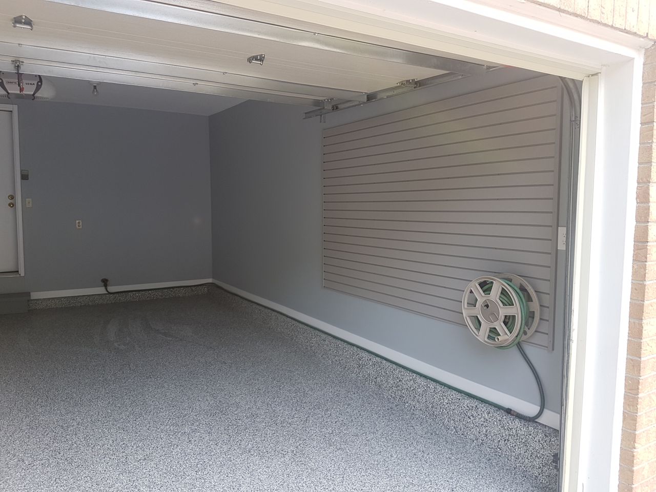 A finished Ottawa double garage with grey slatwall on every wall, a tall steel cabinet and a flake-coated floor
