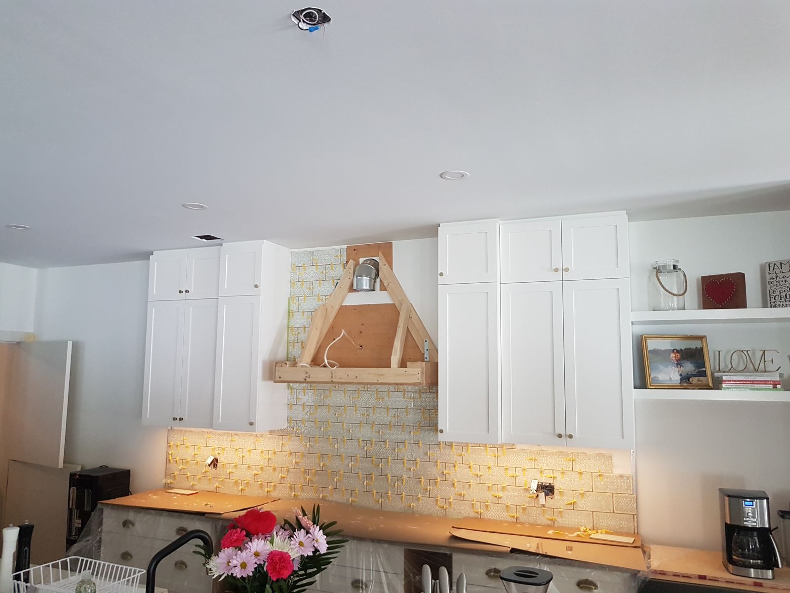 White shaker kitchen with a wood range hood and patterned tile, built by Home Upgraders